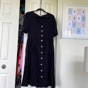 Midi length black dress with buttons and pockets.